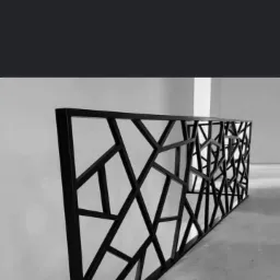 Czarno-biała fotografia metalowej balustrady o geometrycznym wzorze, z widoczną strukturą spawanych elementów i minimalistycznym tłem ściany oraz posadzki.