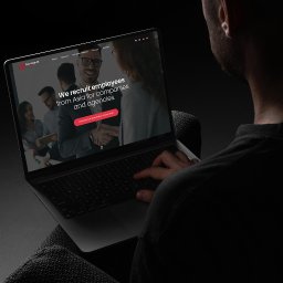 Agencja interaktywna Adverweb - Osoba oglądająca na laptopie stronę internetową firmy Pako Group HR z hasłem 'We recruit employees from Asia for companies and agencies', w ciemnym otoczeniu.