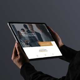 Agencja interaktywna Adverweb - Dłonie trzymające tablet z wyświetloną nowoczesną stroną internetową o pożyczkach pod zastaw nieruchomości dla firm, na ciemnym, stonowanym tle.