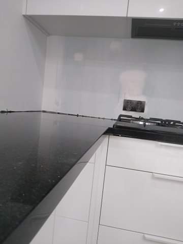 Błyszczący, czarny blat w kuchni z białymi szafkami i płytą grzewczą, widok z niskiego kąta.