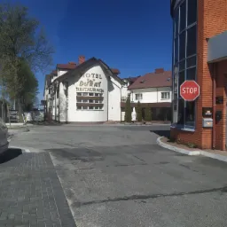 Hotel Durat i Agencja Celna J.K Cargo na jednym zdjęciu, znak STOP przy wejściu do agencji, widok na budynki w słoneczny dzień.