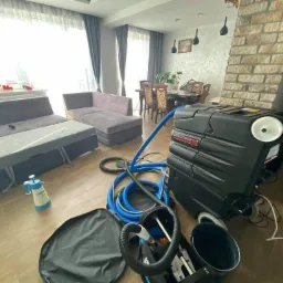 Profesjonalny sprzęt do prania kanap i dywanów w Radomiu, widoczny w przestronnym salonie z szarą sofą i drewnianą podłogą, gotowy do użycia.