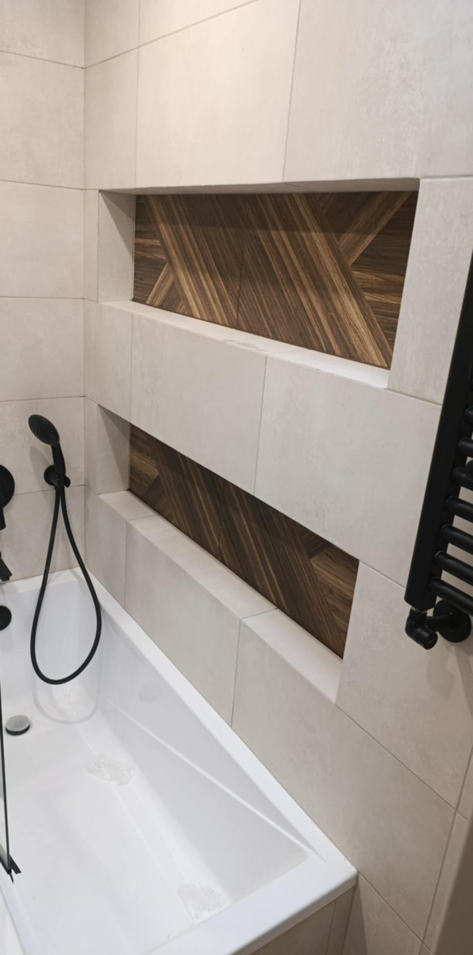 Nowoczesna łazienka z wnękami wykończonymi drewnopodobną mozaiką, białe płytki, czarna armatura i grzejnik. Minimalistyczny design.