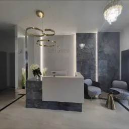 Recepcja kliniki medycyny estetycznej z marmurowymi elementami, oświetleniem LED i złotymi akcentami w postaci lamp i stolika.