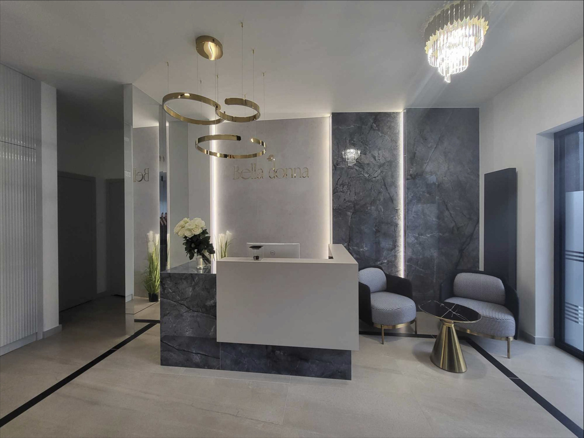 Recepcja kliniki medycyny estetycznej z marmurowymi elementami, oświetleniem LED i złotymi akcentami w postaci lamp i stolika.