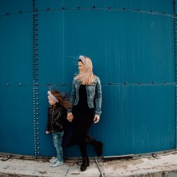 Foto Artist Fotografia Monika Jachowicz - Matka z córką w Łodzi pozują na tle dużej, błękitnej konstrukcji, obie ubrane w kurtki, włosy rozwiane wiatrem.