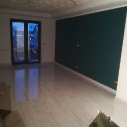 Wnętrze po malowaniu z ciemnozieloną ścianą, widoczne niedoskonałości na suficie i odbicie światła w polerowanej podłodze, w tle okno z widokiem na ośnieżony ogród.