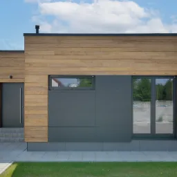 Nowoczesny dom jednorodzinny z drewnianą elewacją i grafitowymi panelami, widoczne schody wejściowe i zadbany trawnik.