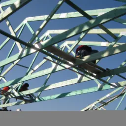 Konstrukcja drewniana dachu w trakcie montażu, dwóch robotników w uprzężach pracuje na wysokości, błękitne niebo w tle.