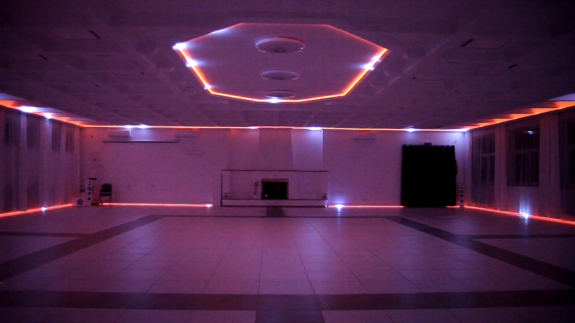 Duża sala z podwieszonym sufitem i oświetleniem LED wzdłuż ścian i sufitu, tworzącym geometryczne wzory.