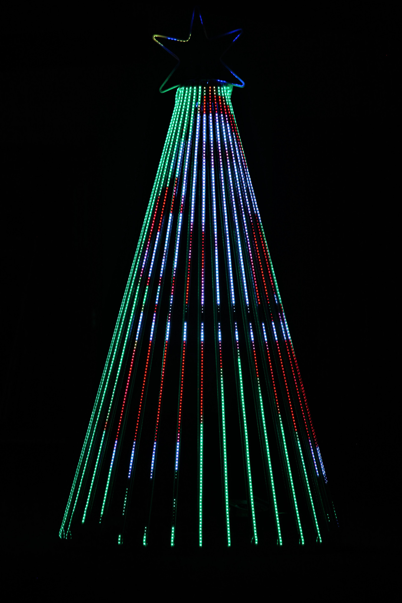 Świąteczna dekoracja w kształcie choinki, zbudowana z pionowych pasków diod LED w kolorach zielonym, niebieskim i czerwonym, zwieńczona gwiazdą z podświetleniem.