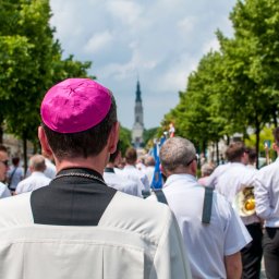 SacroPhoto Wioleta Żurawska - Procesja religijna z widokiem na wieżę kościoła, z perspektywy osoby w różowej piusce.