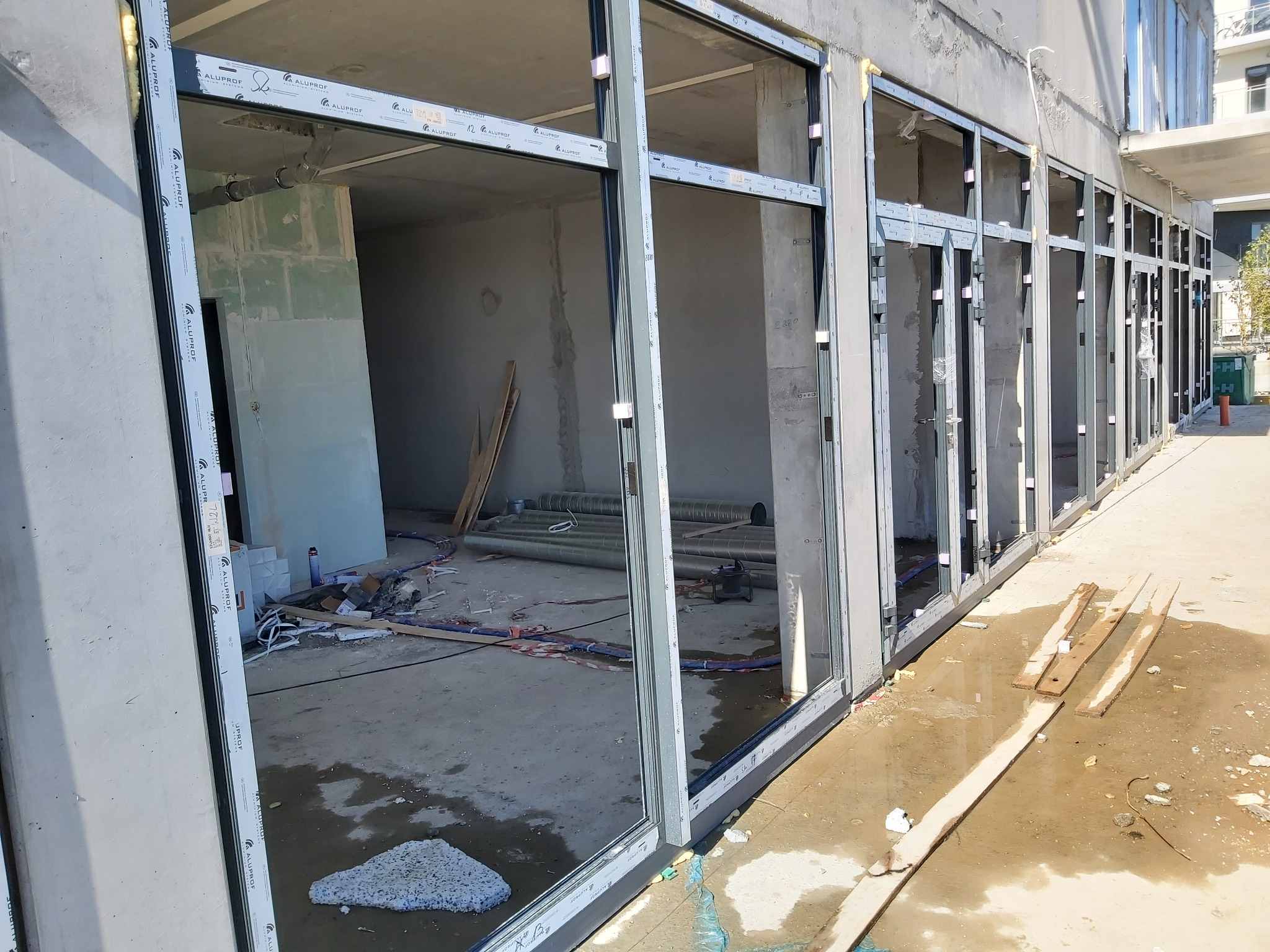 Surowy stan budynku z zamontowanymi ramami okiennymi z profili aluminiowych Alufrof, widoczne elementy montażowe i pozostałości po budowie.