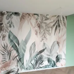 Ściana z fototapetą w motywy roślinne, sąsiadująca z pomalowaną na zielono ścianą, na podłodze parkiet ułożony w jodełkę.