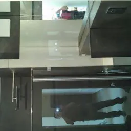 Nowoczesna łazienka z czarno-białymi szafkami i lustrzaną ścianą, w której odbija się osoba robiąca zdjęcie.