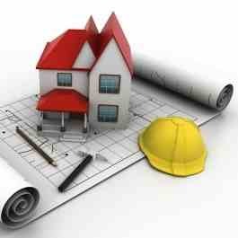 Model domu z czerwonym dachem umieszczony na planie architektonicznym, obok zwinięty plan, ołówek, nóż i żółty kask budowlany, wszystko na białym tle.