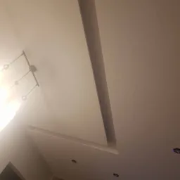 Nowoczesny sufit podwieszany z oświetleniem punktowym i dekoracyjnym wgłębieniem, widok z dołu.