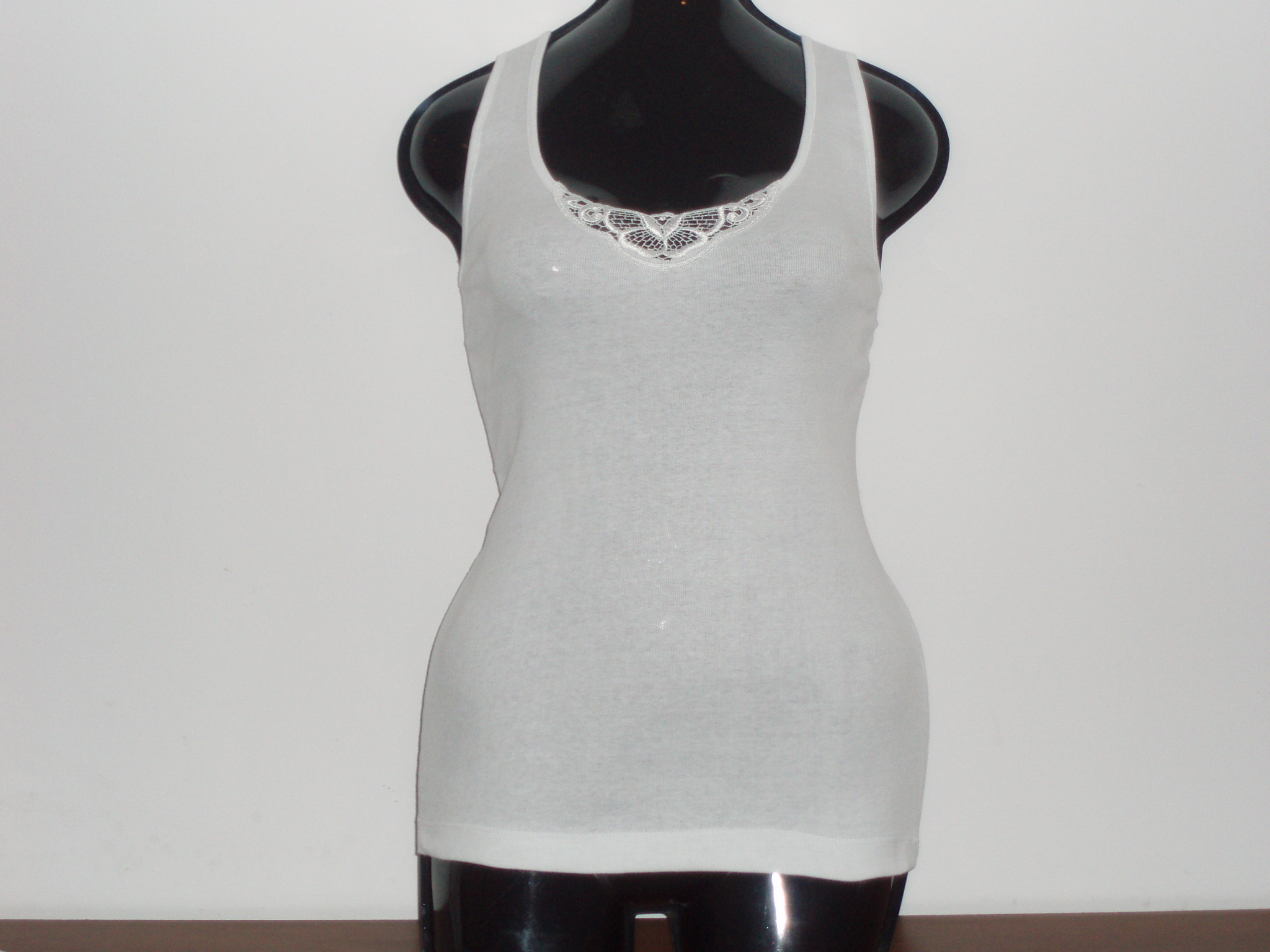 Biały, damski podkoszulek na czarnym manekinie z koronkowym wykończeniem dekoltu.
