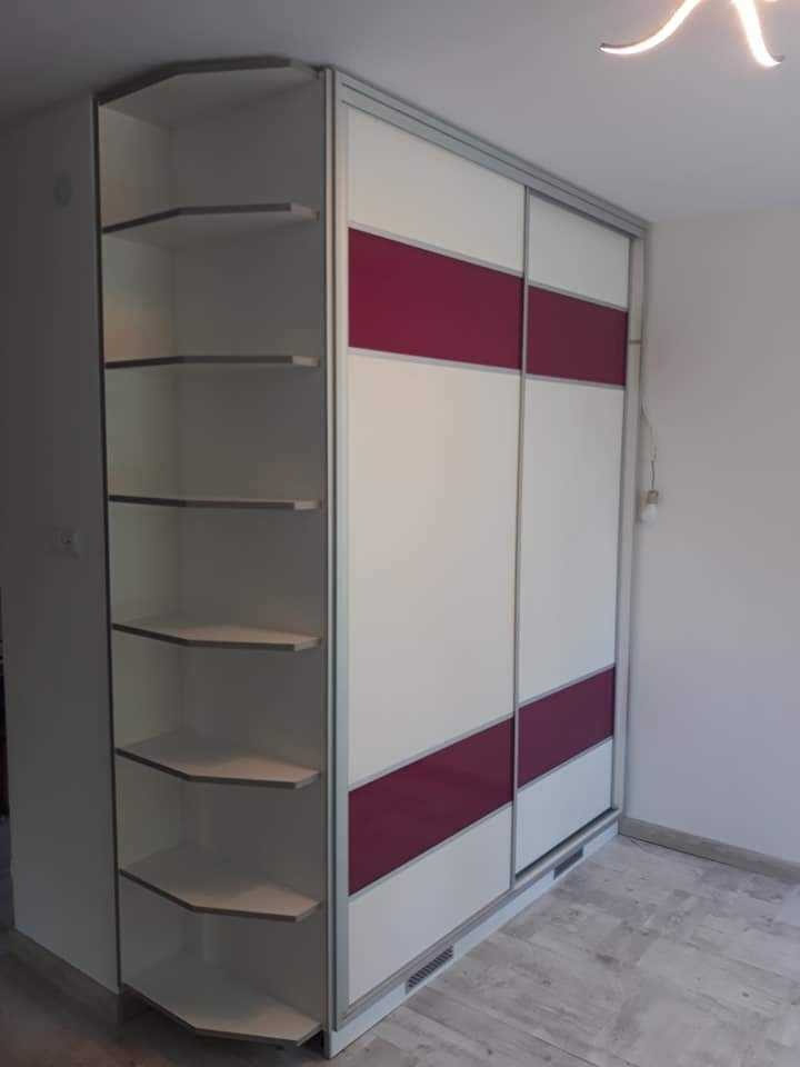 Szafa przesuwna na wymiar z białymi frontami, poziomym pasem w kolorze fuksji i narożnym regałem z półkami.