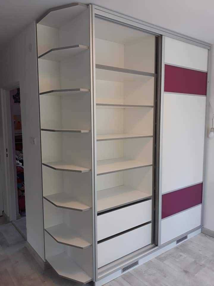 Biała szafa przesuwna z półkami narożnymi i fioletowymi akcentami na drzwiach, widoczna na tle jasnego wnętrza.