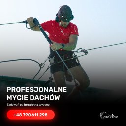 La Creative - Pracownik w uprzęży linowej, w kasku i słuchawkach, czyści dach za pomocą lancy ciśnieniowej, widoczne krople wody w powietrzu, logo firmy na koszulce.