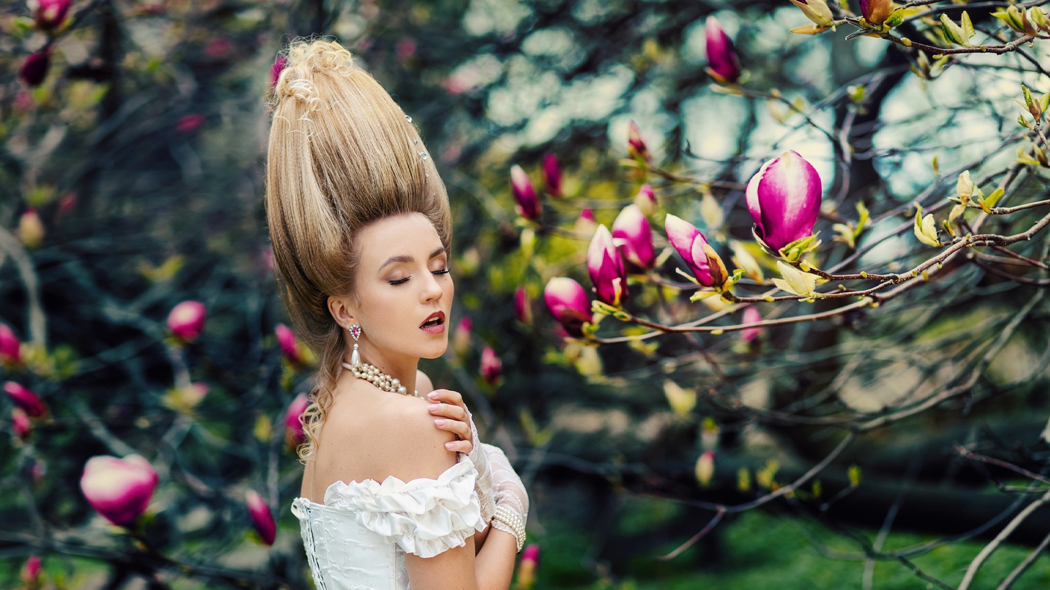 Portret kobiety w stylizowanej sukni i fryzurze z epoki, z zamkniętymi oczami, otoczona kwitnącymi magnoliami, delikatne oświetlenie.