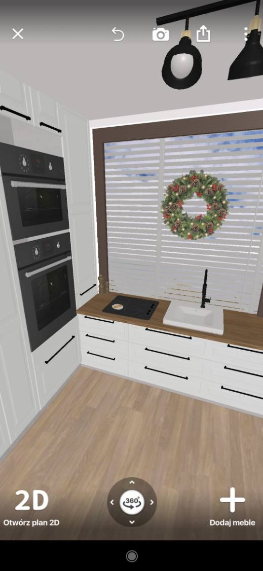 Wizualizacja projektu kuchni w stylu skandynawskim z białymi szafkami, drewnianym blatem, wbudowanymi piekarnikami i świątecznym wieńcem na oknie.