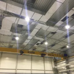 Wnętrze hali produkcyjnej z widoczną konstrukcją stropu, oświetleniem i suwnicą BUDTOR o udźwigu 5t/1,6t.