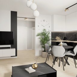 OM Dekor Sylwia Kaczmarek-Bartoszek - Nowoczesne wnętrze: salon z aneksem kuchennym w bieli i czerni. Minimalistyczny design, okrągły stół, marmurowy blat, drewniana podłoga i dekoracyjne panele ścienne.