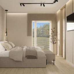 OM Dekor Sylwia Kaczmarek-Bartoszek - Jasna sypialnia z łóżkiem, lampami i TV. Widok na zewnątrz przez okno z żaluzjami. Minimalistyczny design z drewnianymi akcentami i subtelnym oświetleniem.