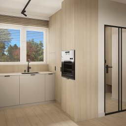 OM Dekor Sylwia Kaczmarek-Bartoszek - Jasna kuchnia z drewnianymi frontami, minimalistycznym oświetleniem i oknem z widokiem na drzewa. Nowoczesny piekarnik w zabudowie i czarne akcenty.