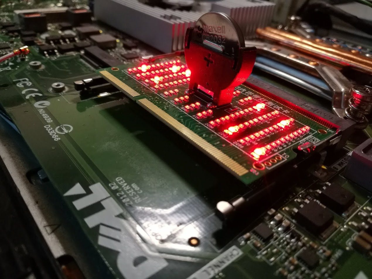 Płyta główna komputera Dell z testerem pamięci RAM podświetlonym czerwonymi diodami LED i baterią Maxell CR2032.