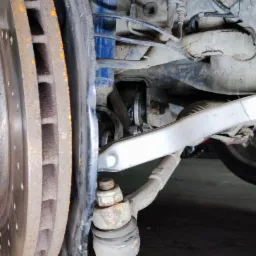 Zawieszenie samochodu z widoczną skorodowaną tarczą hamulcową, amortyzatorem i elementami układu kierowniczego w warsztacie w Krzymowie.