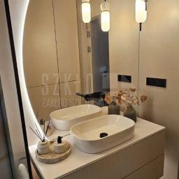 Szkło Zakład Szklarski S.C. Krystyna Bańkowska - Jaz, Marek Jaz - Nowoczesna łazienka z owalnym lustrem LED, podwójną umywalką nablatową i wiszącą szafką z ryflowanym frontem. Minimalistyczne lampy wiszące.