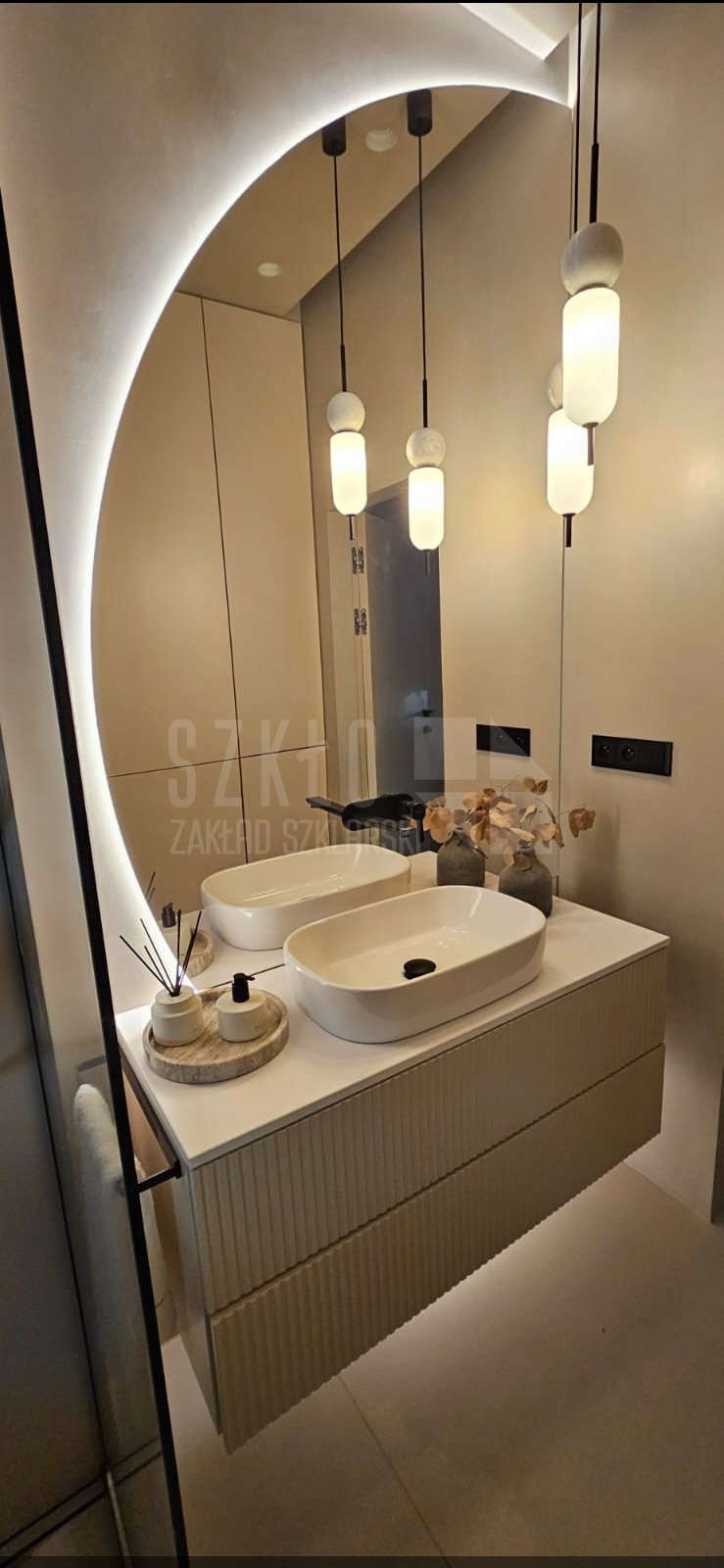 Nowoczesna łazienka z owalnym lustrem LED, podwójną umywalką nablatową i wiszącą szafką z ryflowanym frontem. Minimalistyczne lampy wiszące.