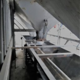 ELCON Electris Adam Łoś - Wnętrze konstrukcji stalowej, być może w trakcie budowy lub konserwacji, z widocznymi elementami nośnymi i podtrzymującymi, ujęcie z dołu, z fragmentem białego elementu w dolnej części kadru.