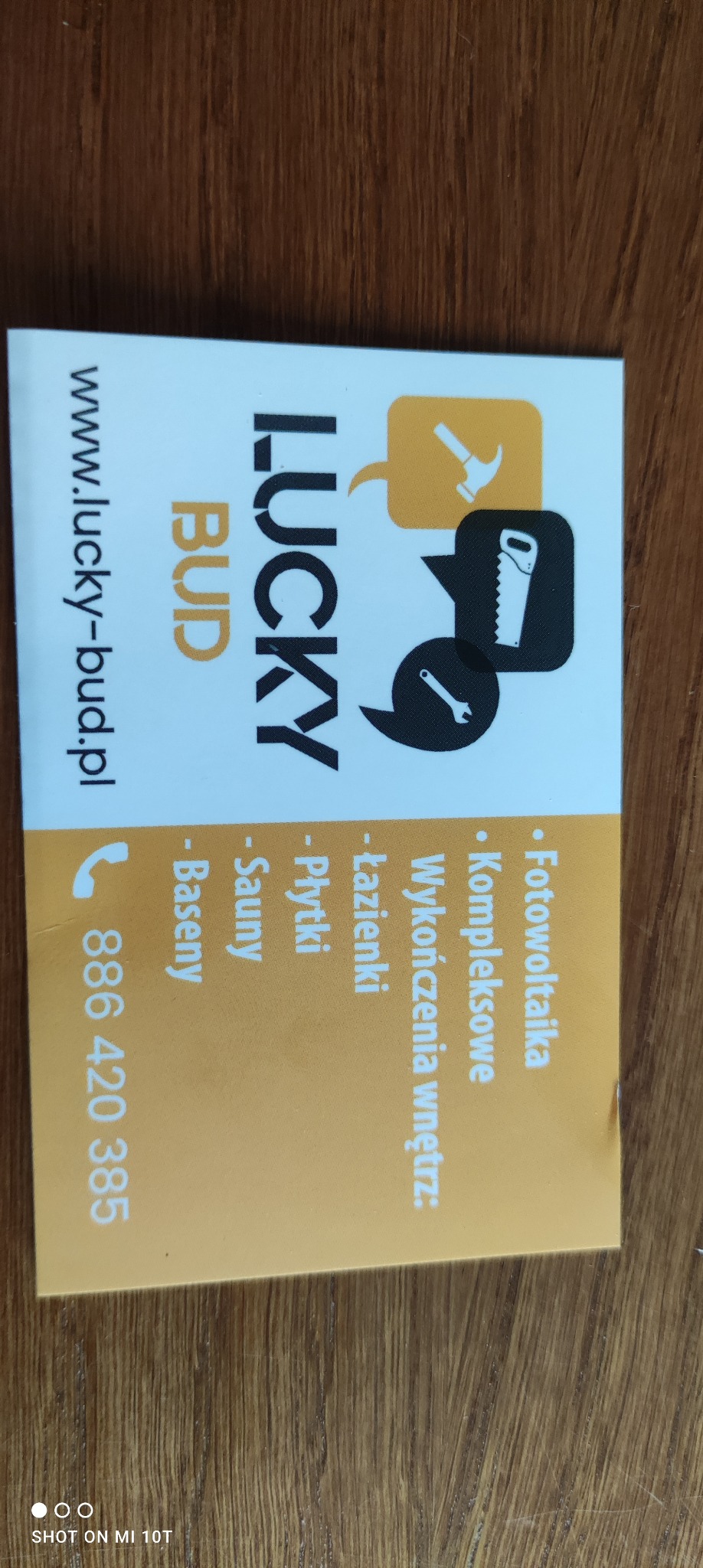 Wizytówka firmy budowlanej Lucky Bud z ikonami narzędzi (młotek, piła, klucz) i listą usług: fotowoltaika, kompleksowe wykończenia wnętrz łazienki, płytki, sauny, baseny oraz adres strony...