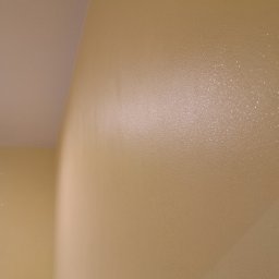 Firma usługowa Arniko - Ściana w odcieniach beżu, świeżo po malowaniu, z widoczną fakturą i delikatnym połyskiem. Ujęcie z bliska, ukazujące gładką powierzchnię i precyzję wykonania.