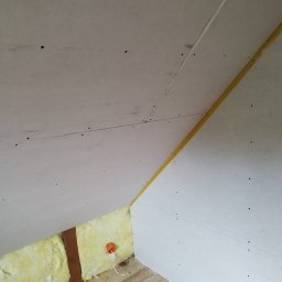 Firma usługowa Arniko - Skośny sufit poddasza z płyt karton-gips, widoczne łączenia wzmocnione taśmą, ocieplenie z wełny mineralnej, drewniana podłoga i instalacja elektryczna.