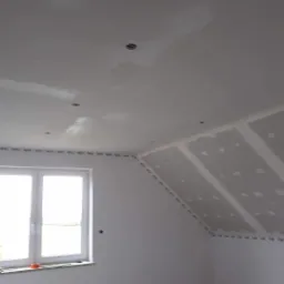 Poddasze w Tucholi w trakcie prac wykończeniowych, widoczne płyty gipsowo-kartonowe na skosach oraz przygotowane otwory na oświetlenie w suficie.