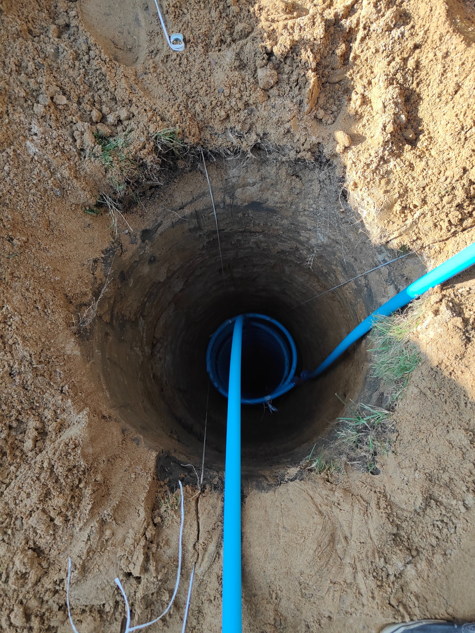 Wykop w ziemi z widocznymi niebieskimi rurami, prawdopodobnie instalacja pod pompę ciepła w Dobrzycy.