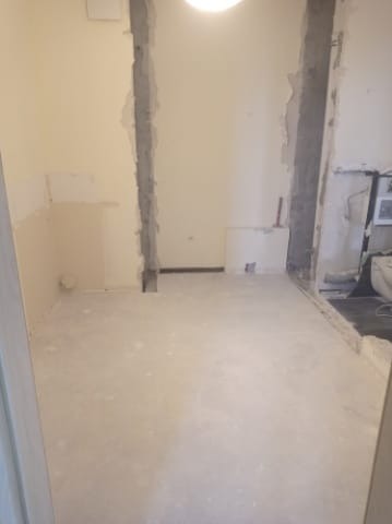 Wnętrze w trakcie wyburzania ścian, widoczne fragmenty ścian usunięte do konstrukcji nośnej, odsłonięty beton i instalacje.