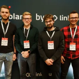 Grupa czterech mężczyzn z identyfikatorami 'Adboosters' pozuje na tle z logo 'SEO Poland by linkhouse' podczas wydarzenia branżowego.