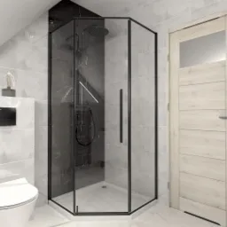 Nowoczesna łazienka na poddaszu z kabiną prysznicową walk-in z czarnymi profilami, wiszącą toaletą i marmurowymi płytkami w odcieniach szarości i czerni.