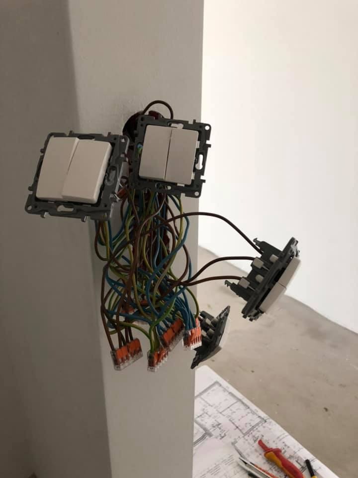 Montaż podwójnych włączników światła: widoczne przewody, złączki WAGO i plan instalacji na podłodze.