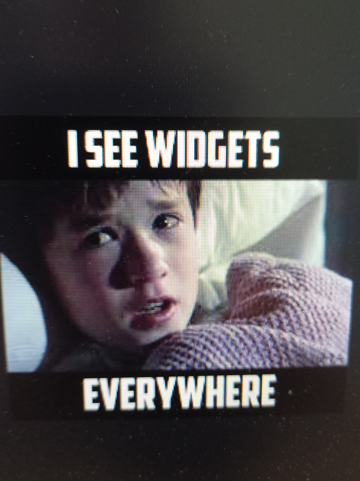 Przerażony chłopiec w łóżku, z tekstem 'I SEE WIDGETS EVERYWHERE' u góry i u dołu kadru.