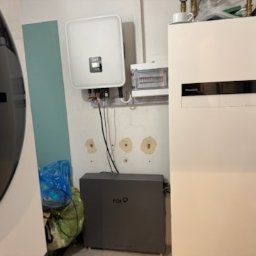 Wichary technic - Zestaw urządzeń: inwerter, rozdzielnica i akumulator Fox, tworzące instalację do magazynowania energii. Białe ściany, widoczne przewody.