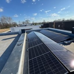 Wichary technic - Panele słoneczne na płaskim dachu domu jednorodzinnego w słoneczny dzień. Widok z góry, lekki kąt. Czyste niebo, nowoczesna architektura w tle.