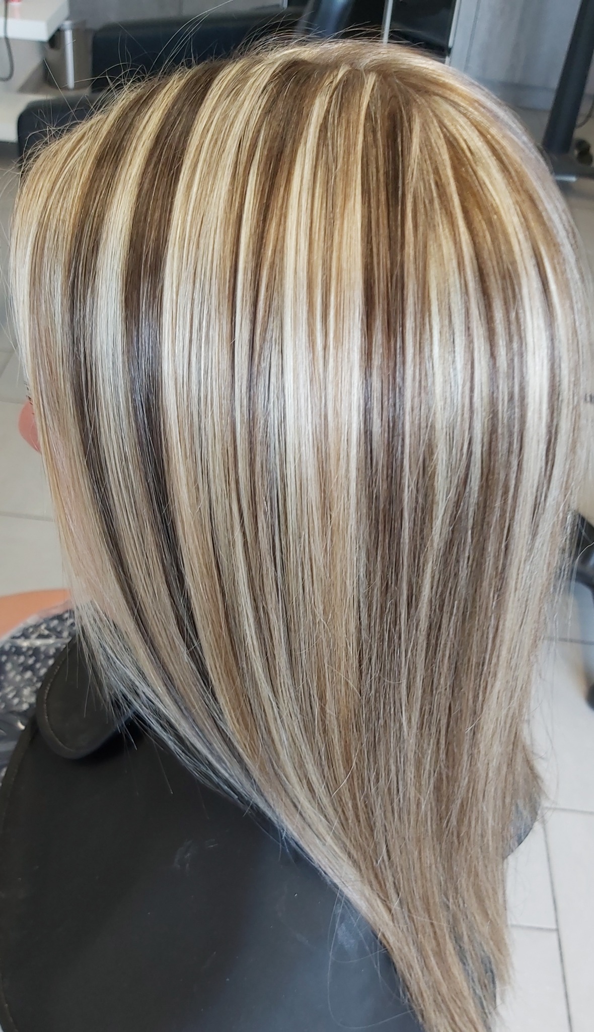 Blond włosy z brązowymi pasemkami, widoczne od tyłu, w salonie fryzjerskim.