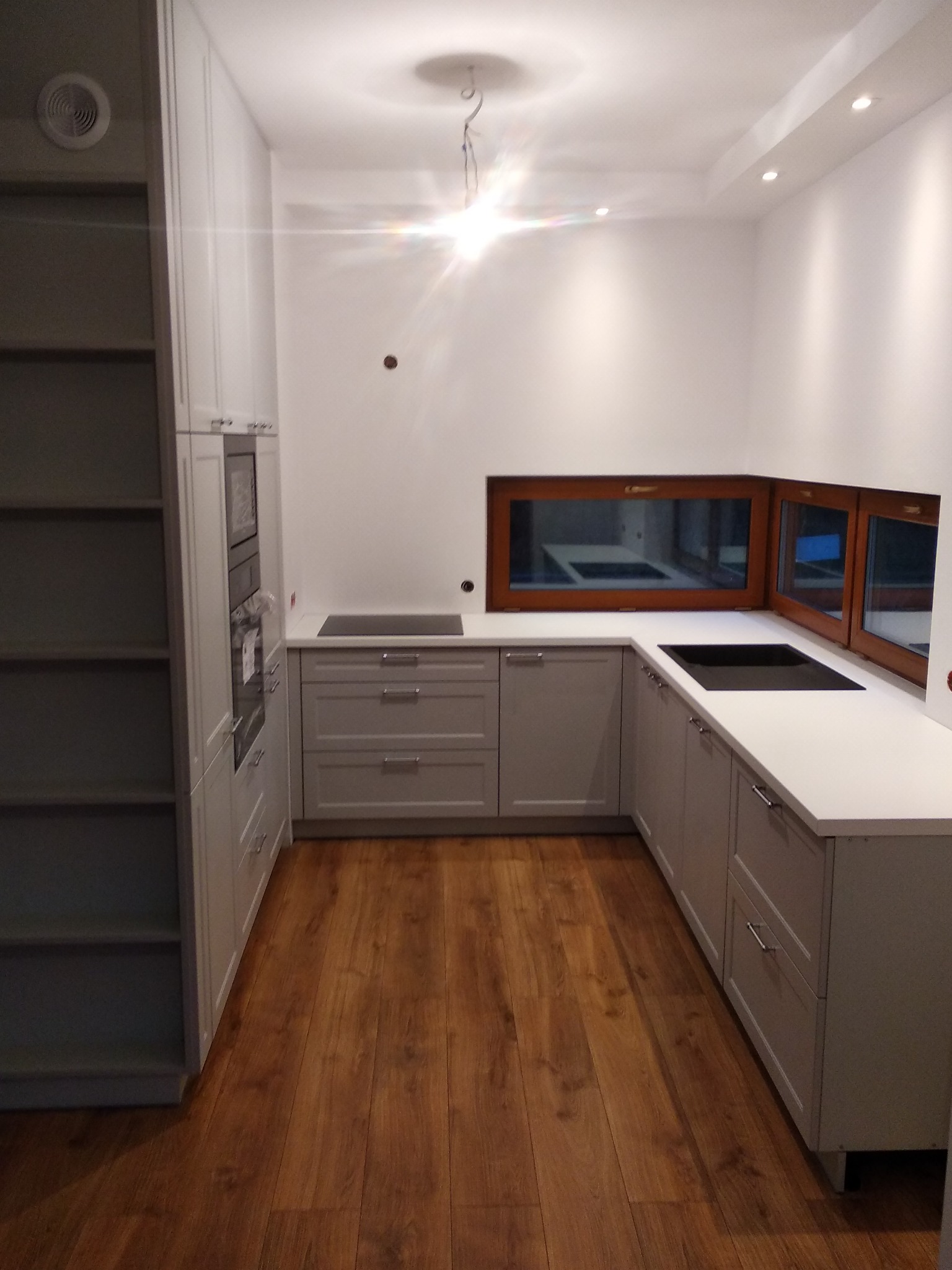 Frezowane fronty lakierowane, blat wpuszczany pod okno zastępuje tradycyjny parapet i poszerza pole robocze.